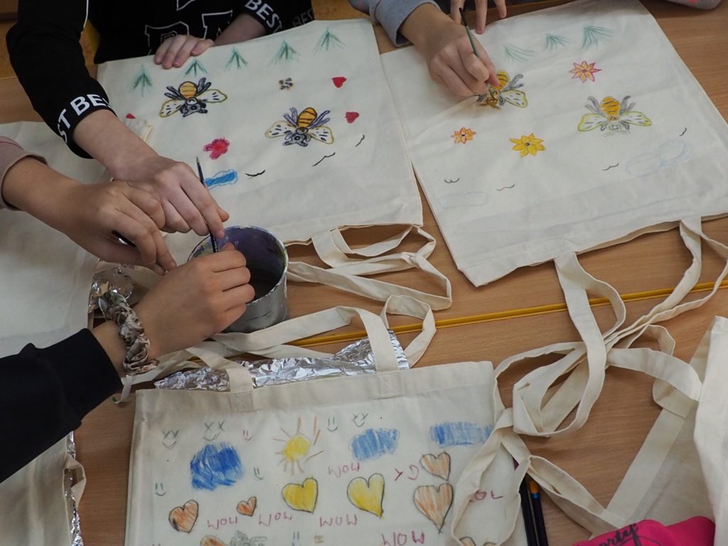 Dłonie zdobiące torby farbami do tkanin