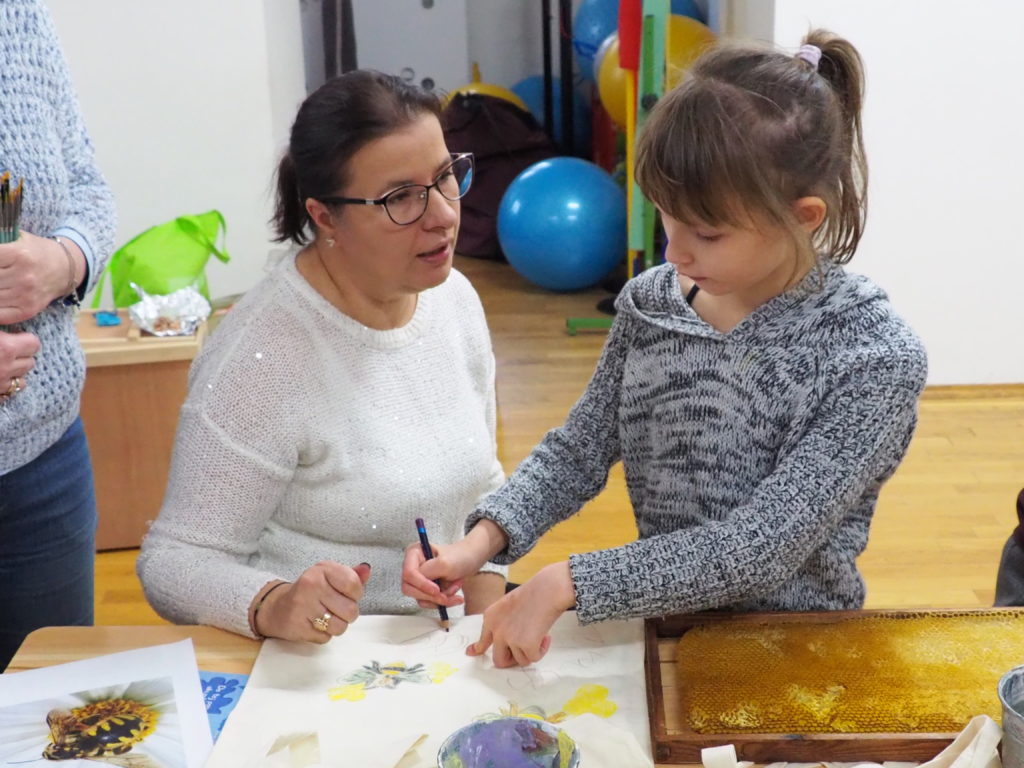 Dziewczynka malująca swoją pracę wraz z nauczycielką
