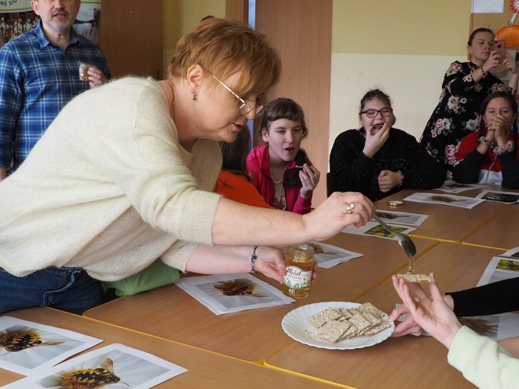 Prowadząca warsztaty częstuje uczestników miodem